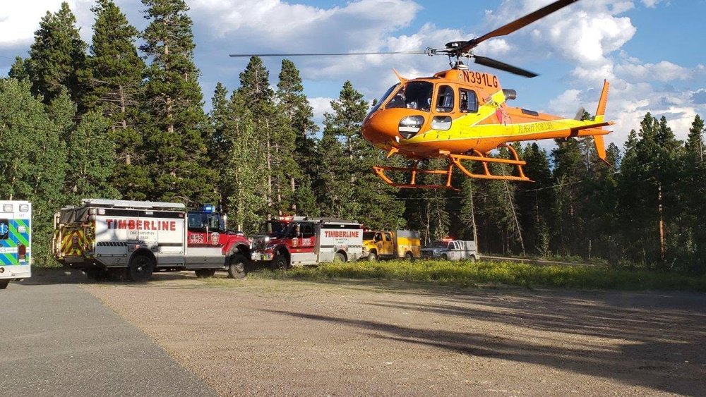 Flight for Life helicopter lifting off next to staged Timberline fire engines